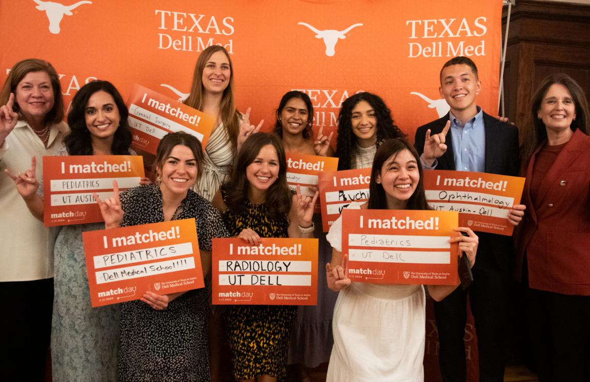 group of students posing with signs for match day in front of a dell medical school burnt orange backdrop